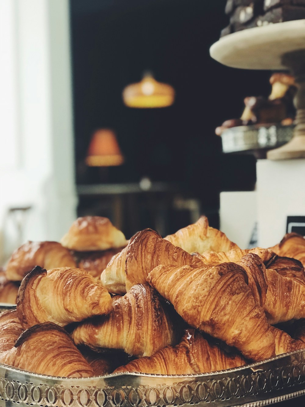 A generous tray of flaky golden croissants beside the bakery window